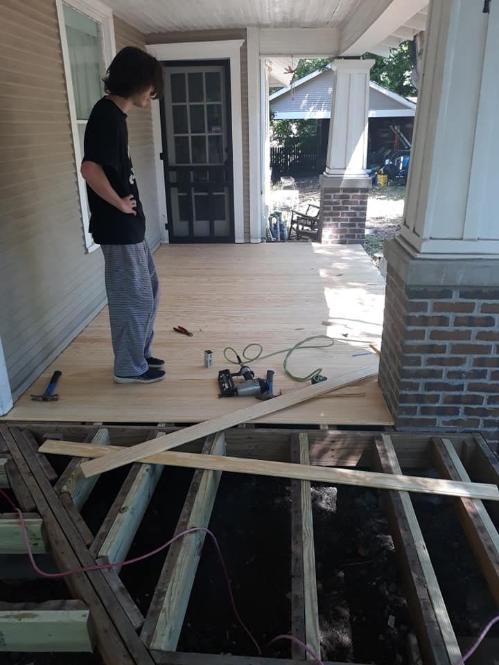 A boy is standing on a wooden deck under construction.