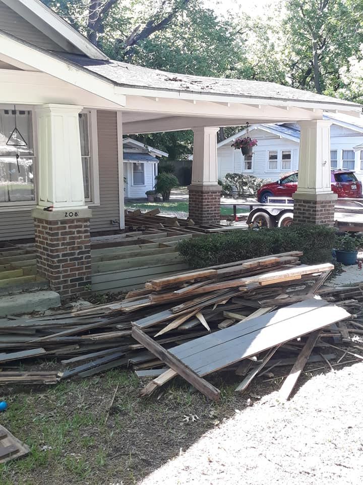 A pile of wood is sitting in front of a house.