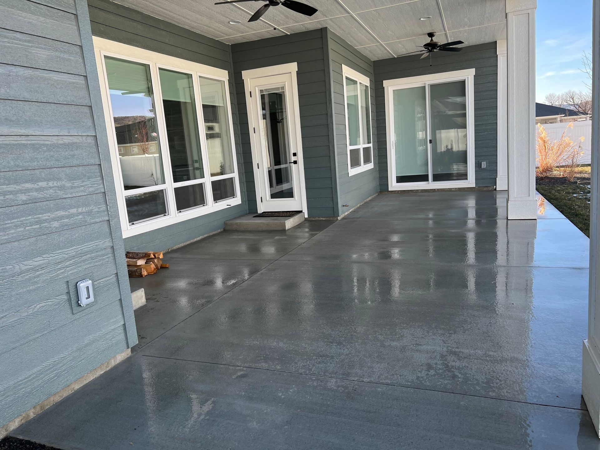 A large porch with a ceiling fan and sliding glass doors on a house.