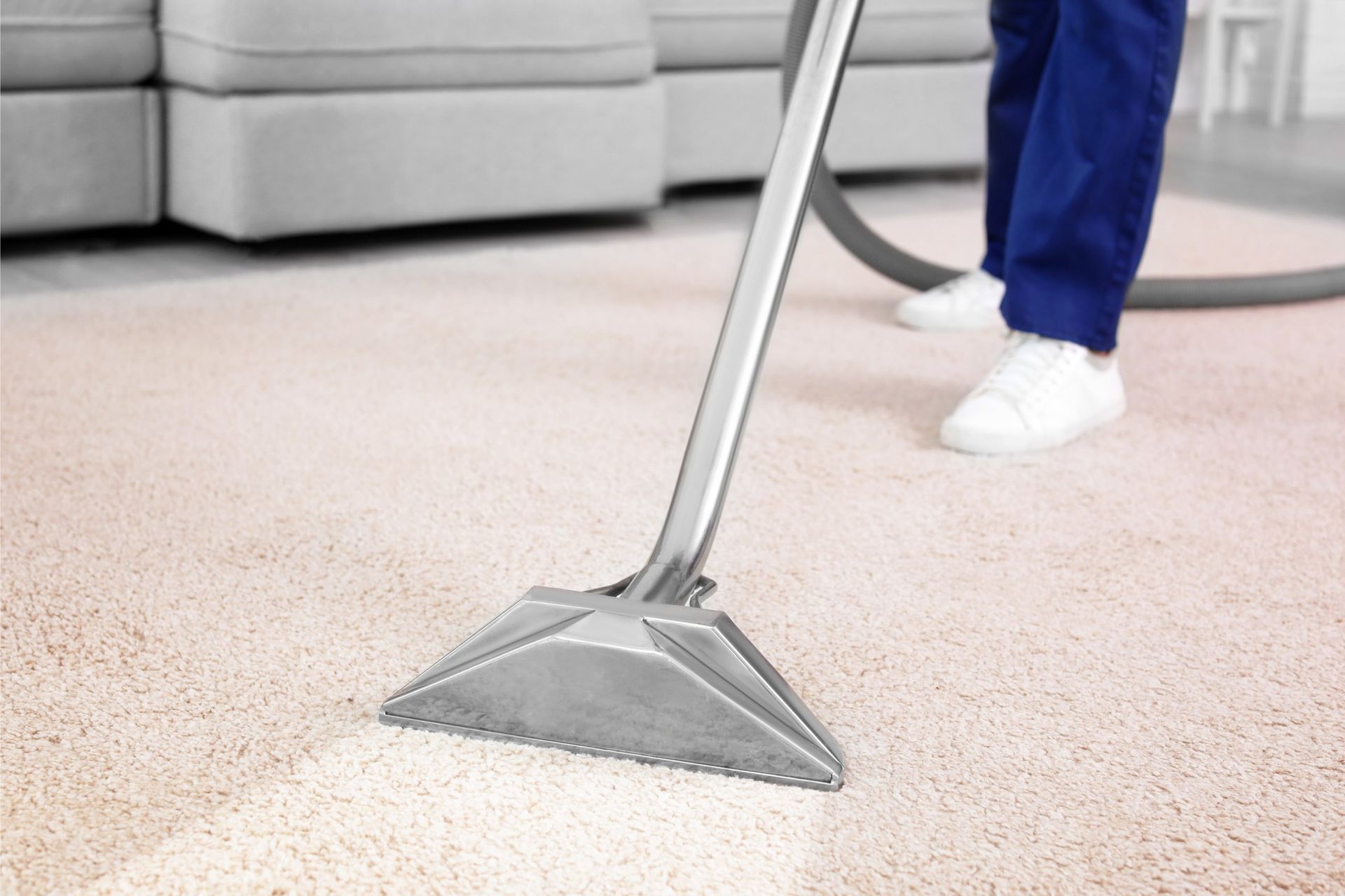 Person using a carpet cleaner on a light-colored rug in a living room