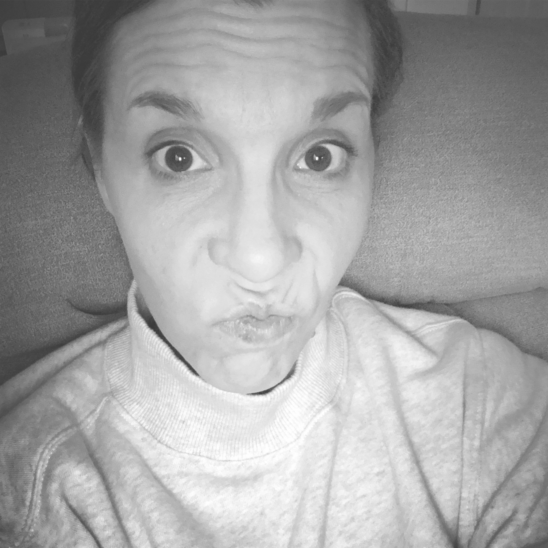 black and white of amy frustrated face with pursed lips sitting  in tan recliner.  Hair pulled back.