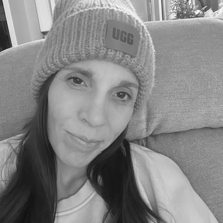 Amy in black in white photo with ugg stocking cap sitting in recliner. 