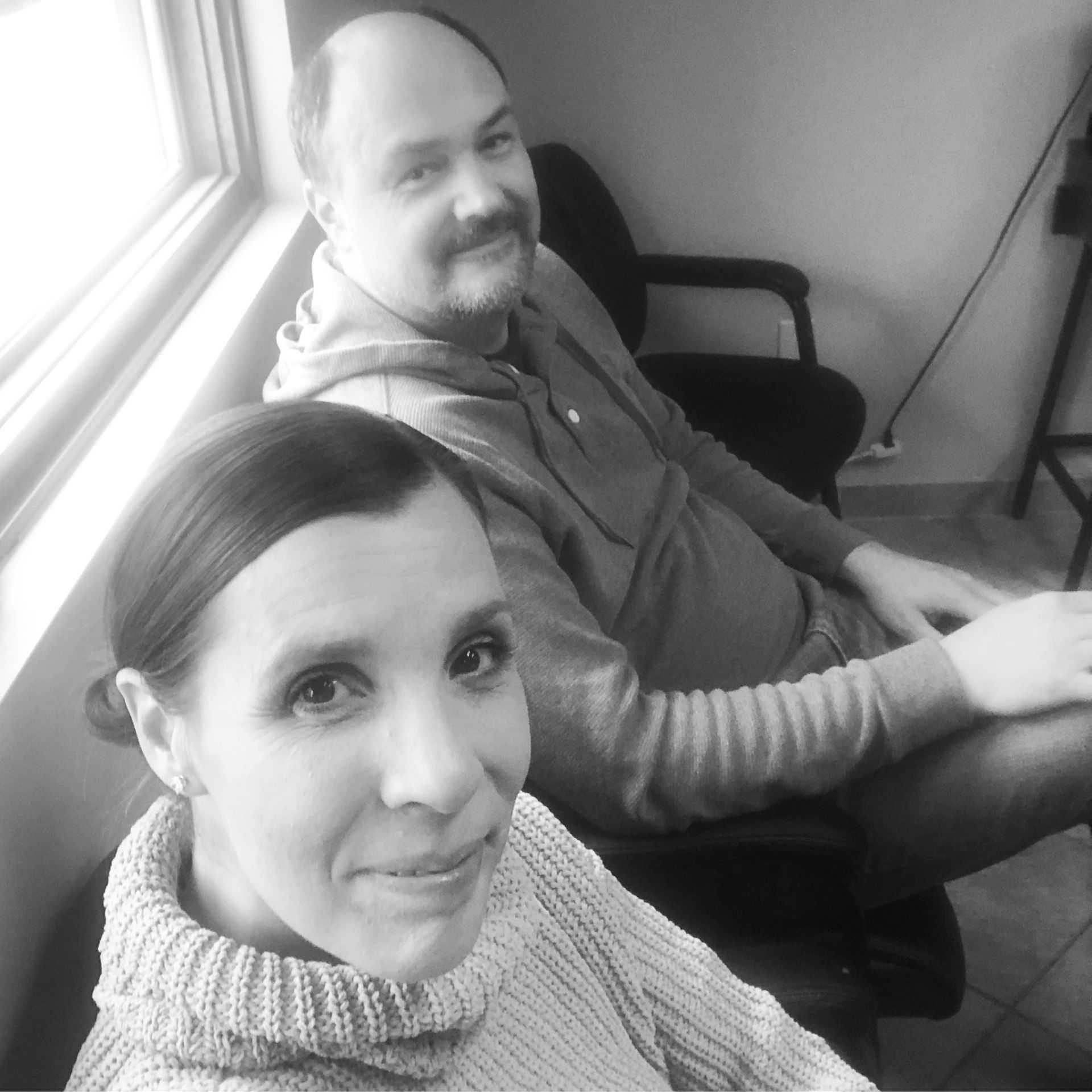 Black and white selfie image of Amy and her husband smiling at the camera in the waiting room.