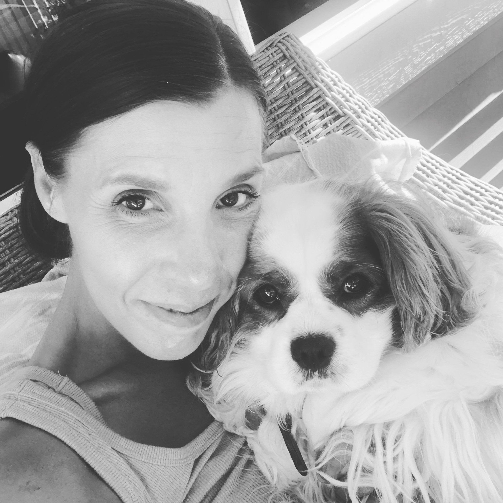 amy dog sitting outside. Black and white photo on porch. Amy is smiling.