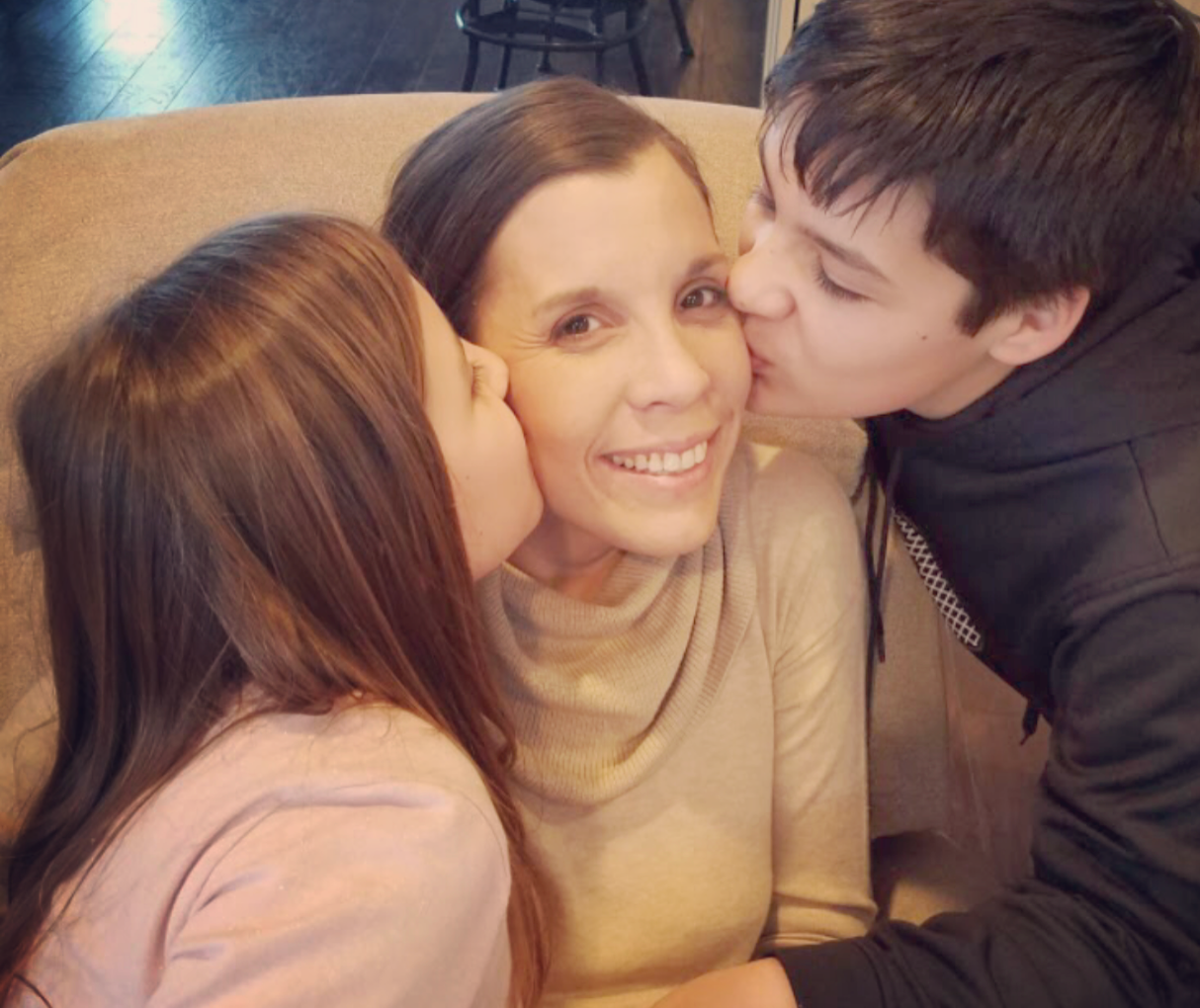 all are a series of photos this one ella and mason are kissing Amy on the cheek. She has big smile.