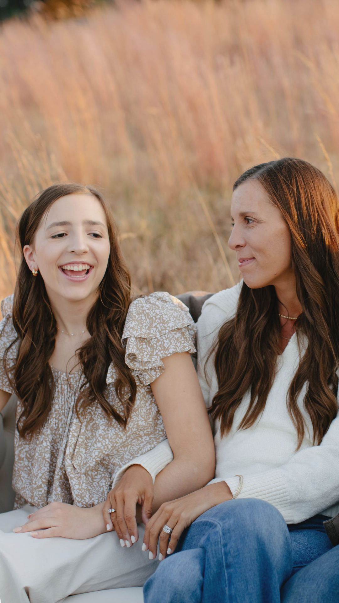 Amy looking at daughter and both smiling in a field of grass 