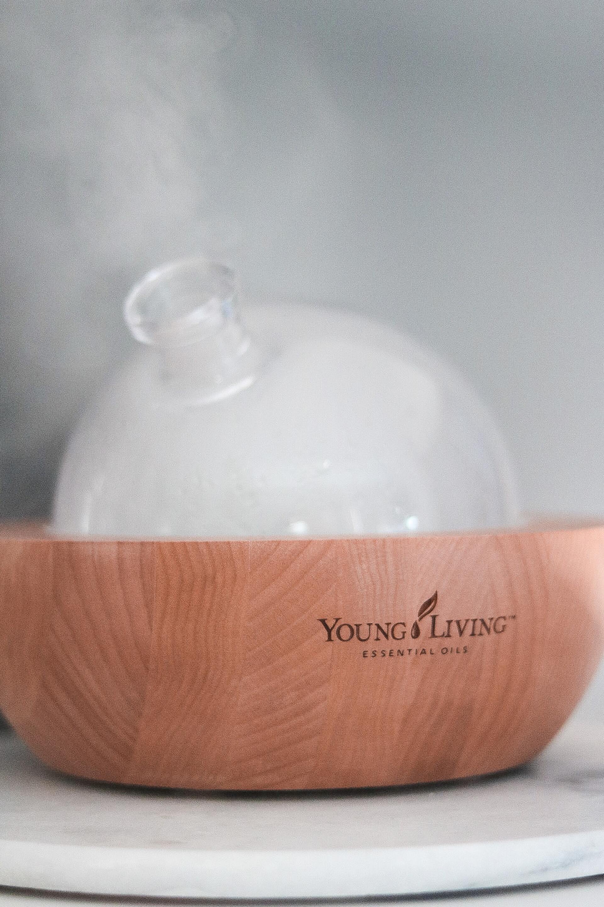 aria young living diffuser brown base and glass top diffusing oils.  Young Living logo on base