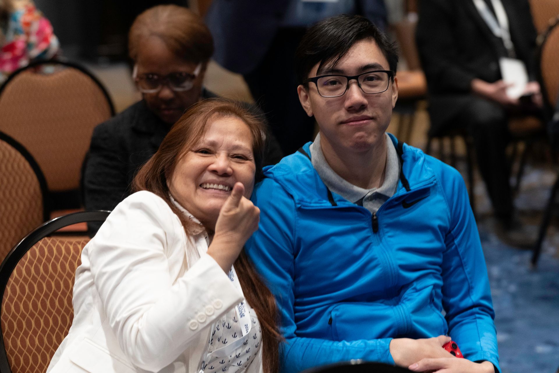 A woman is sitting next to a man in a blue jacket.