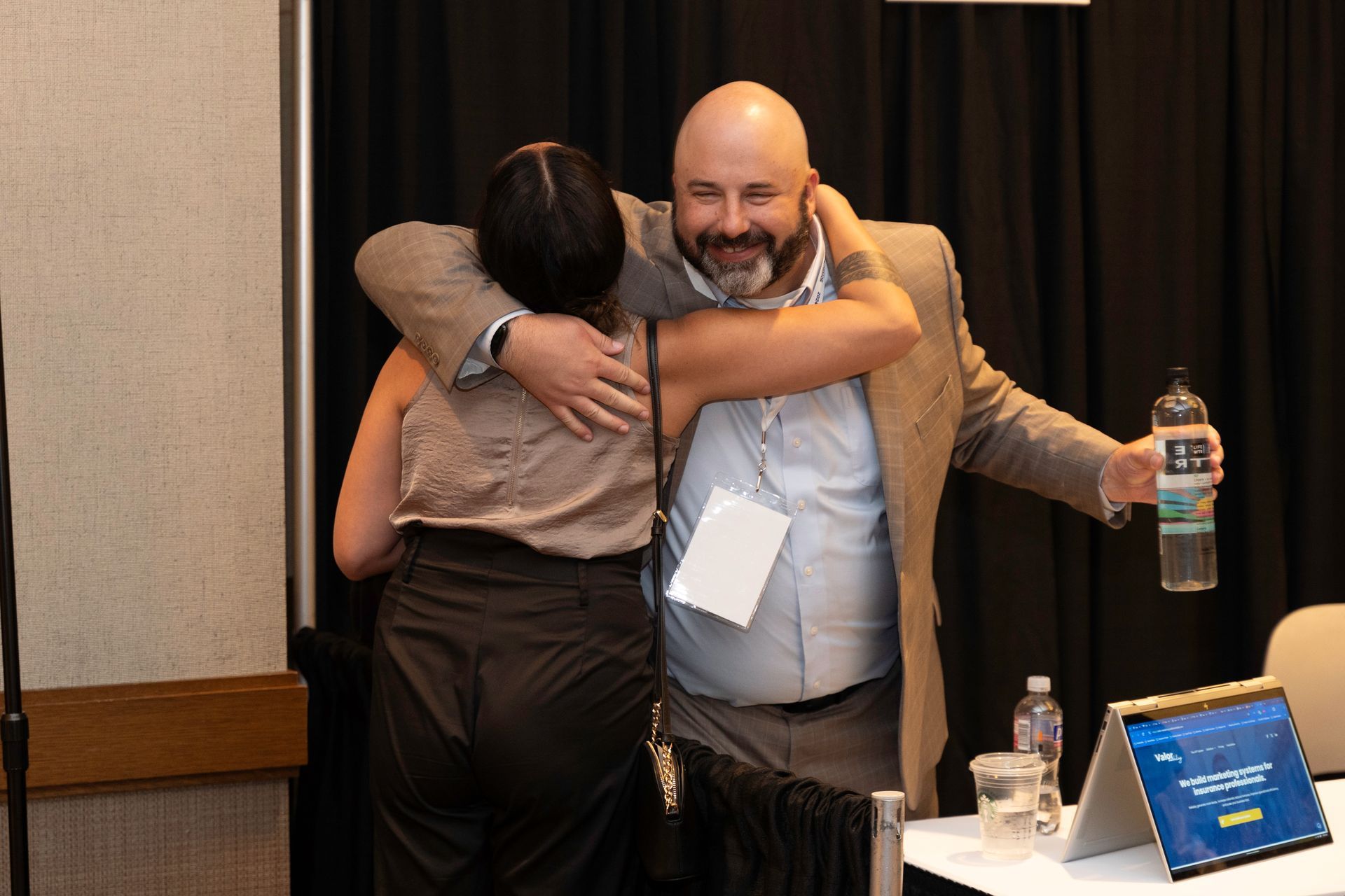 A man is hugging a woman while holding a bottle of water.