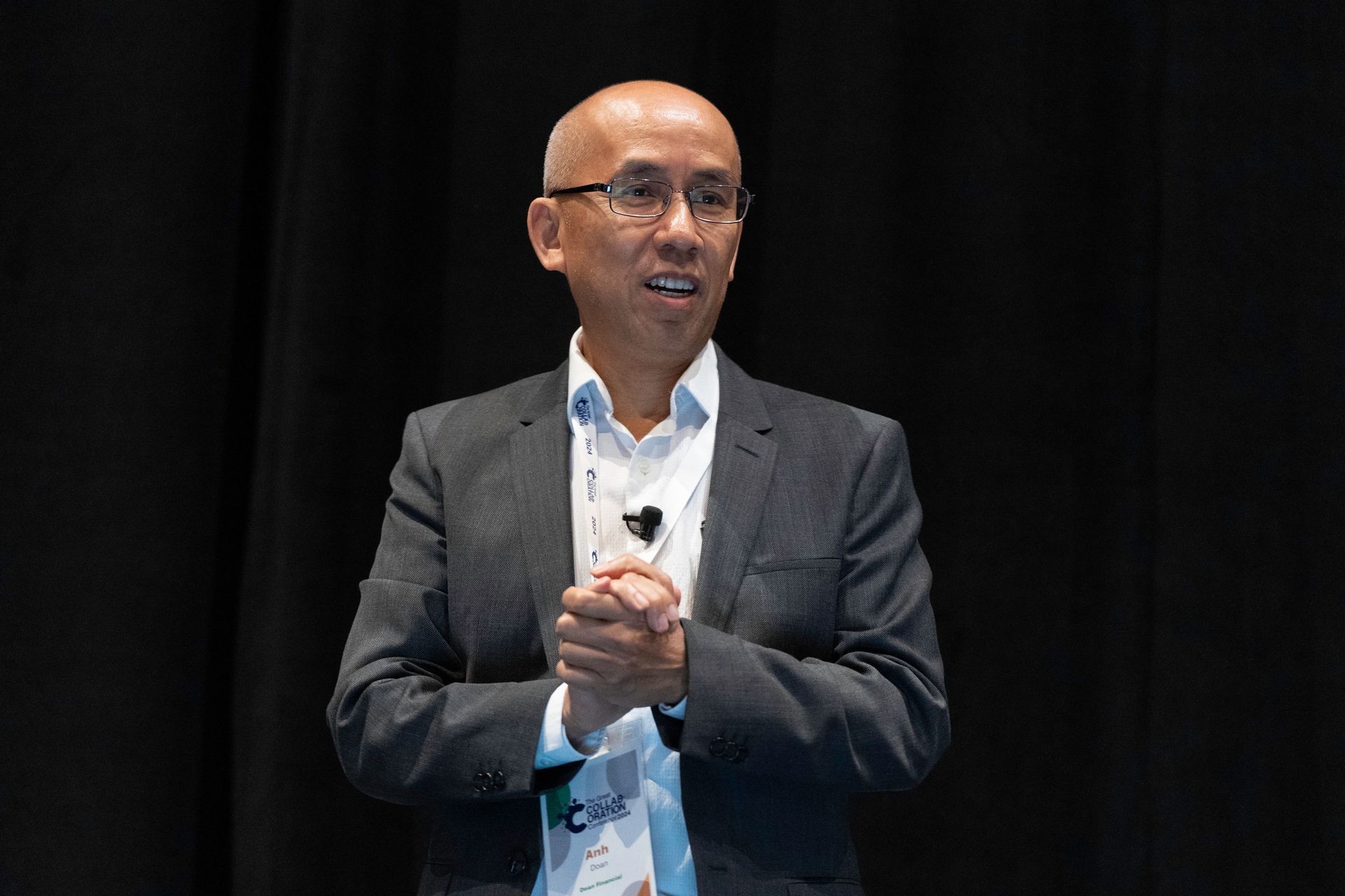 A man in a suit and glasses is giving a speech on a stage.
