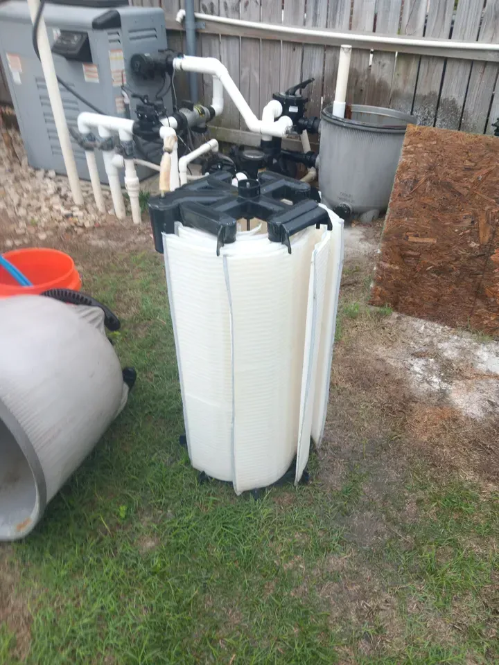 A large white tank is sitting on top of a lush green field.