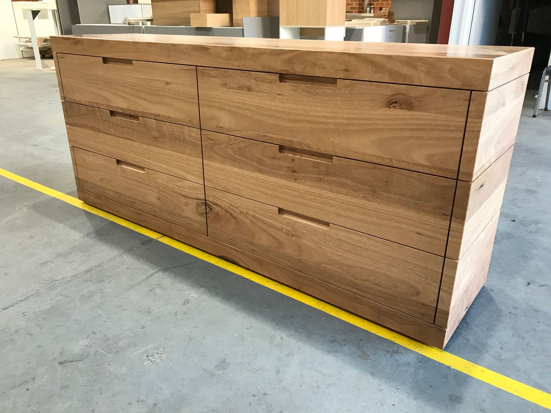 A wooden chest of drawers with a yellow tape measure along the bottom — Marlix Custom Timber Furniture Design and Joinery in Unanderra, NSW