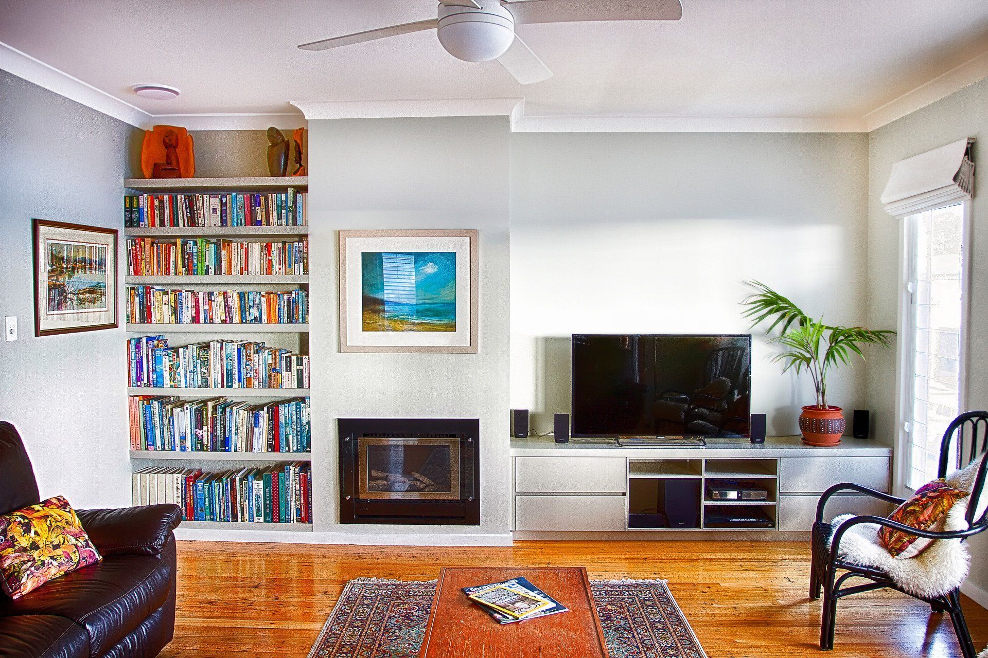 A Living Room with A Couch, Chair, Television, Fireplace and Bookshelves — Marlix Custom Timber Furniture Design and Joinery in Unanderra, NSW