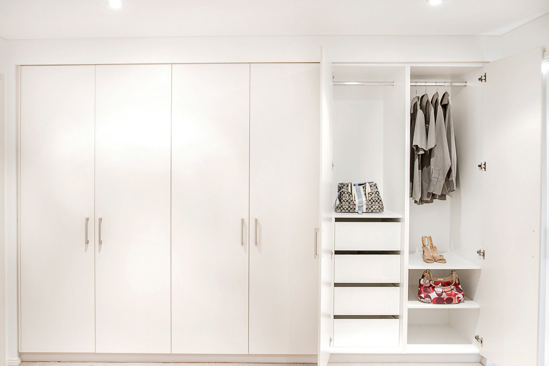 A White Wardrobe with Clothes and A Purse in It — Marlix Custom Timber Furniture Design and Joinery in Unanderra, NSW