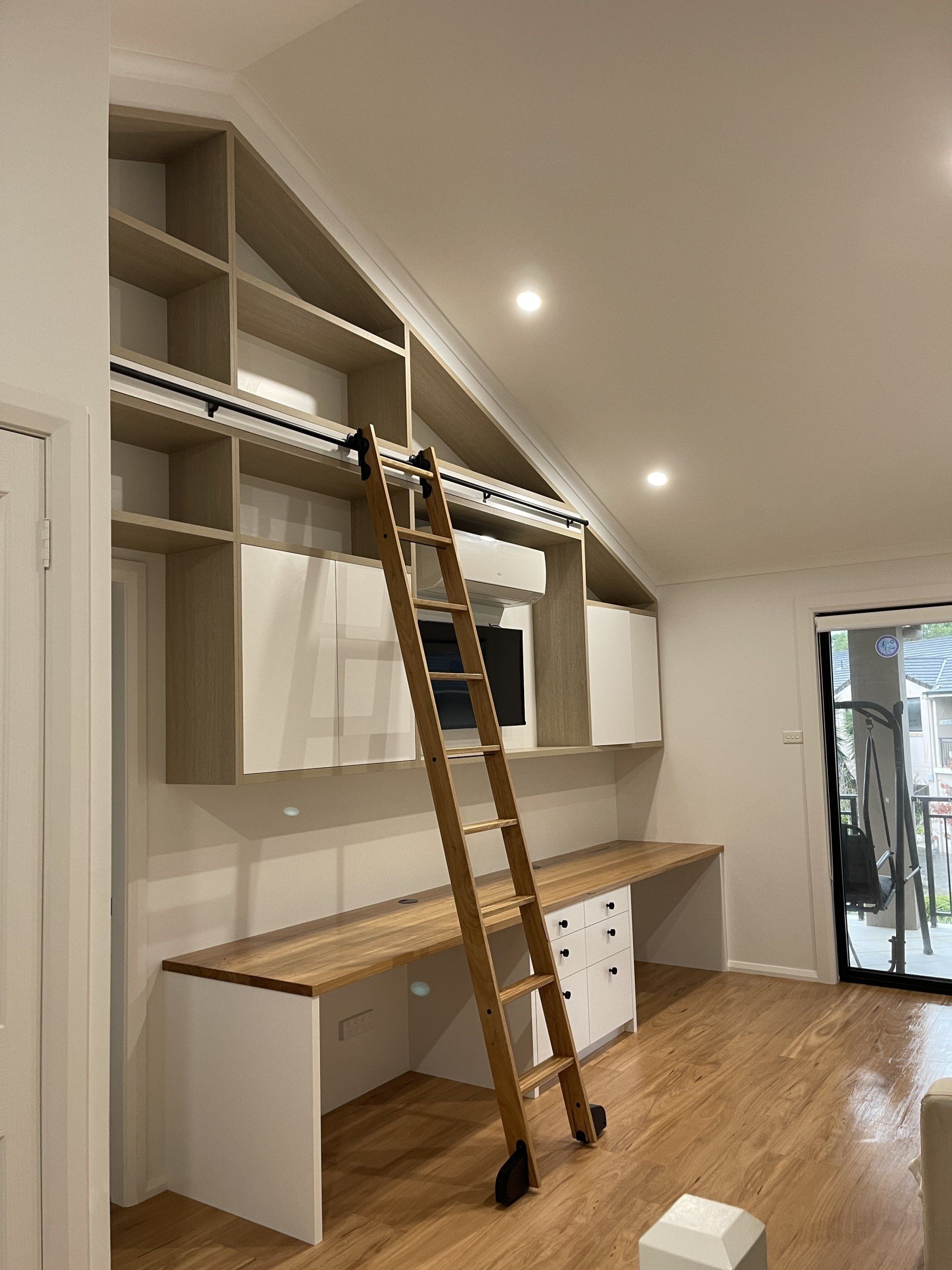 A Living Room with A Ladder Leading up To a Desk and Shelves — Marlix Custom Timber Furniture Design and Joinery in Unanderra, NSW