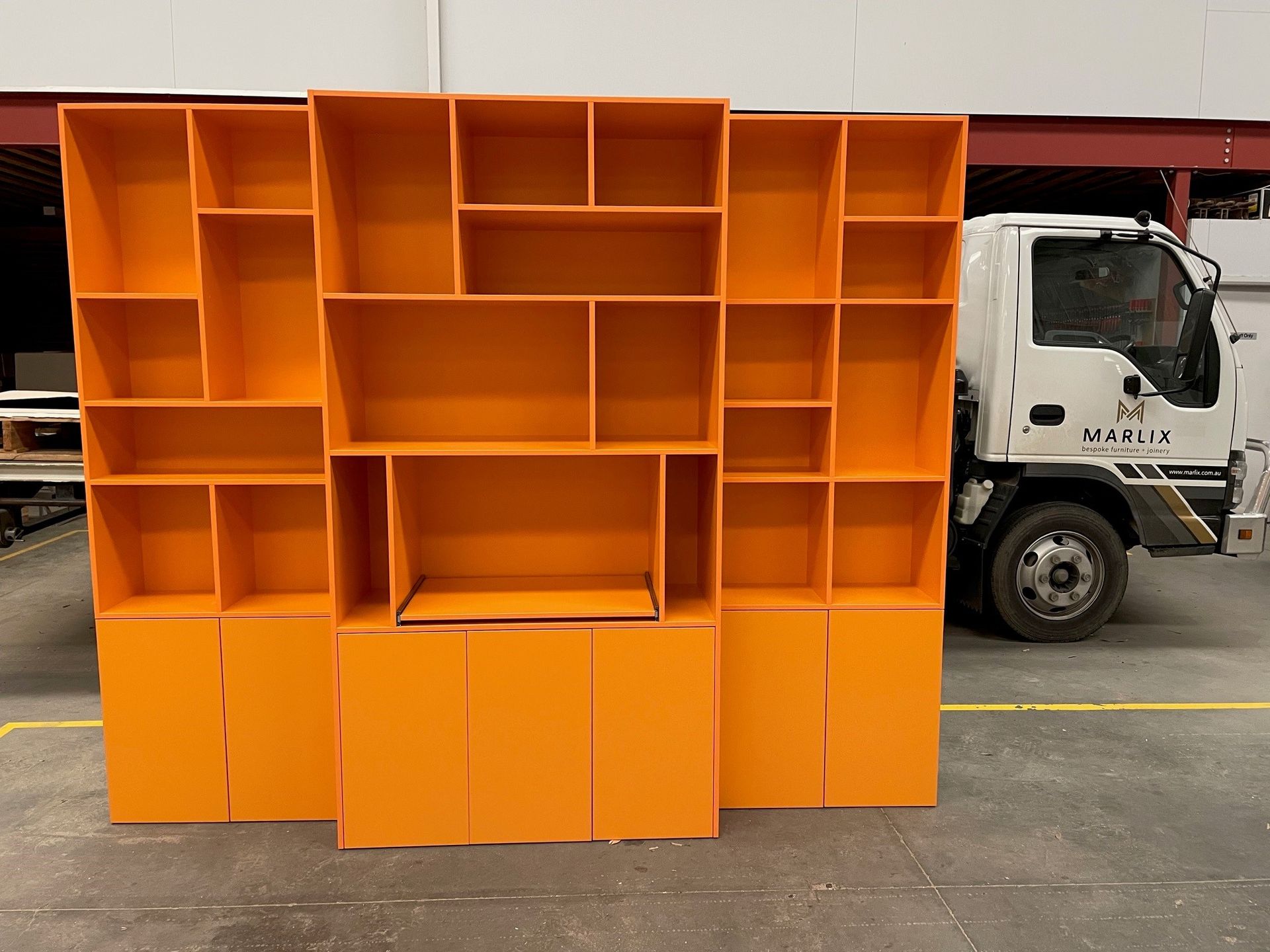 A Truck Is Parked Next to A Row of Orange Shelves — Marlix Custom Timber Furniture Design and Joinery in Unanderra, NSW