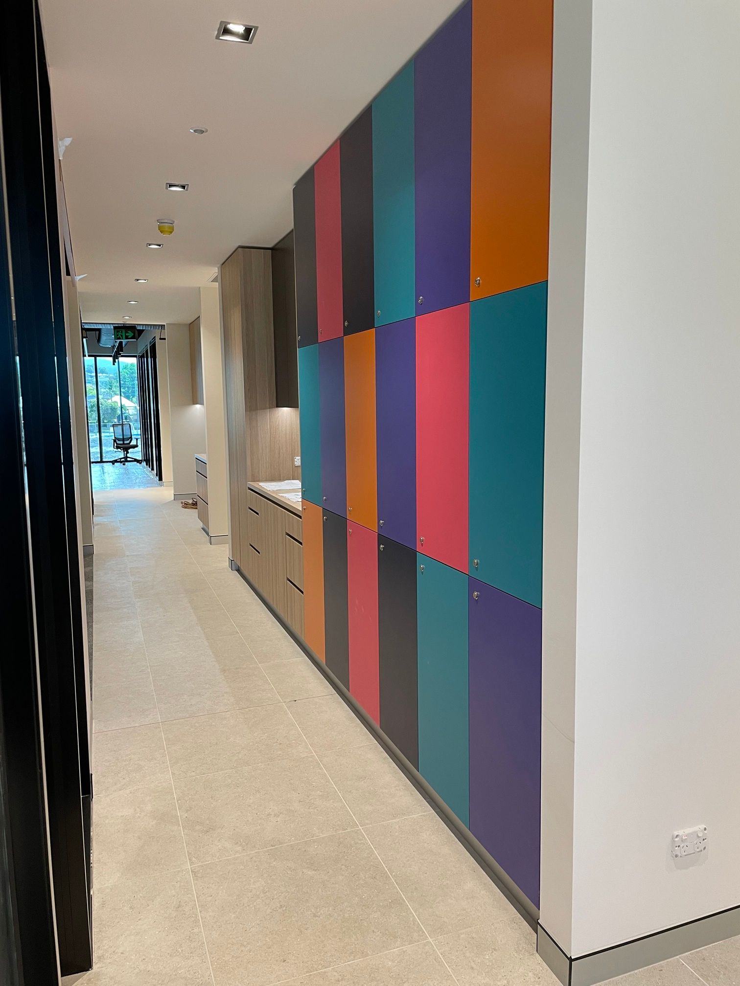 A Hallway with A Lot of Colourful Cabinets on The Wall — Marlix Custom Timber Furniture Design and Joinery in Unanderra, NSW
