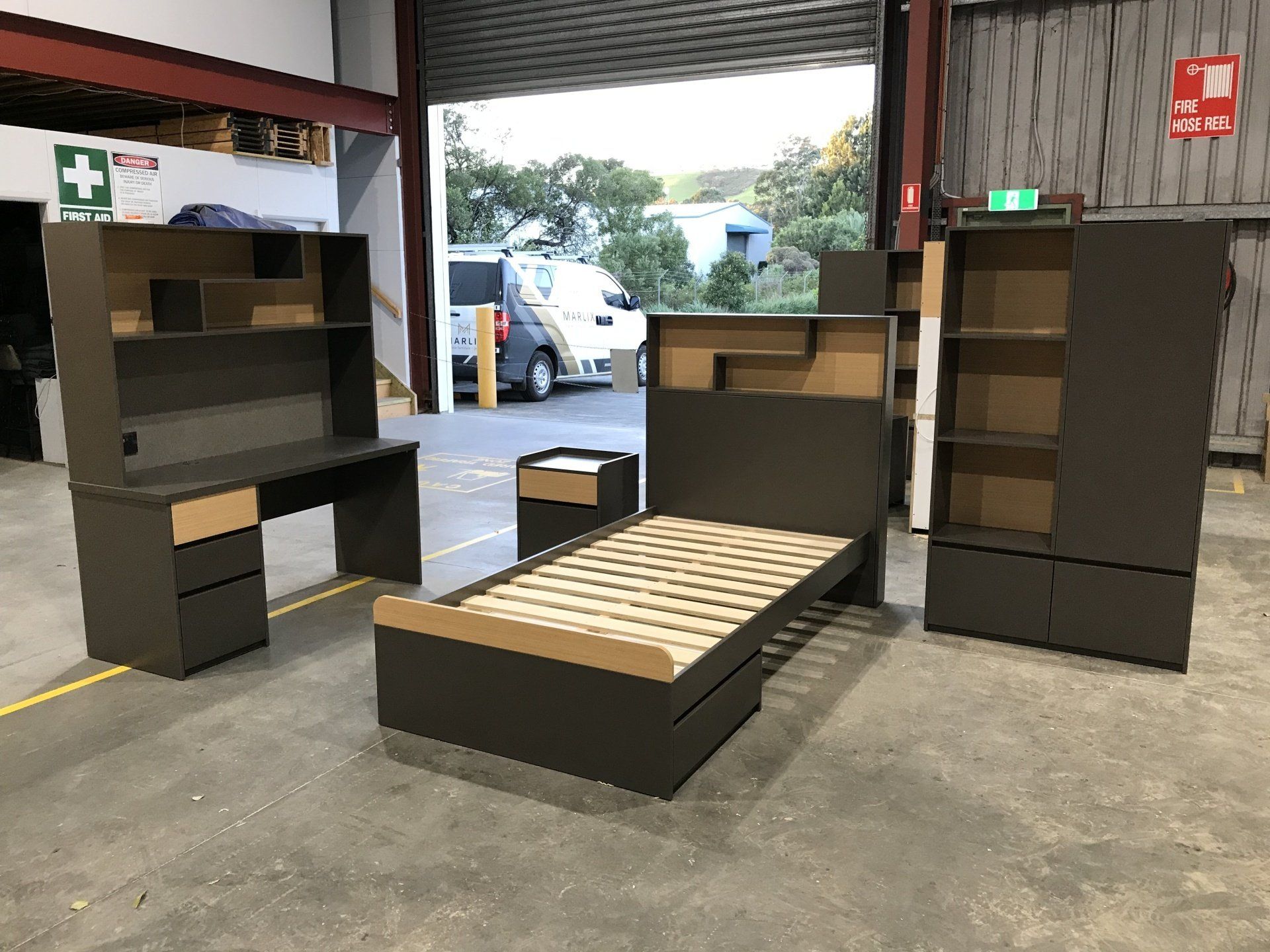 A Bedroom Set With A Bed, Desk, Nightstand And Wardrobe In A Warehouse — Marlix Custom Timber Furniture Design and Joinery in Unanderra, NSW