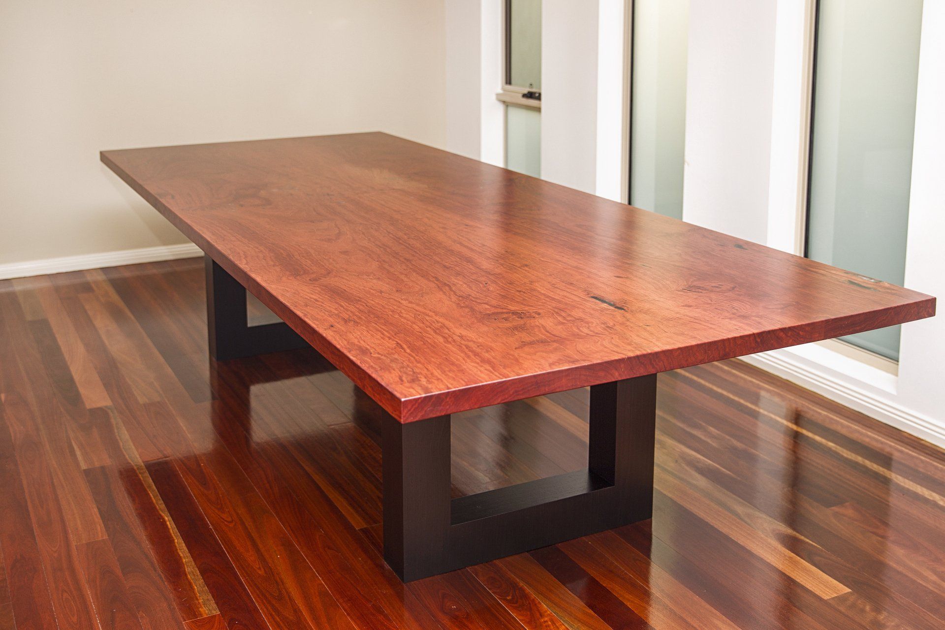A Long Wooden Table Is Sitting On A Wooden Floor In A Room — Marlix Custom Timber Furniture Design and Joinery in Unanderra, NSW