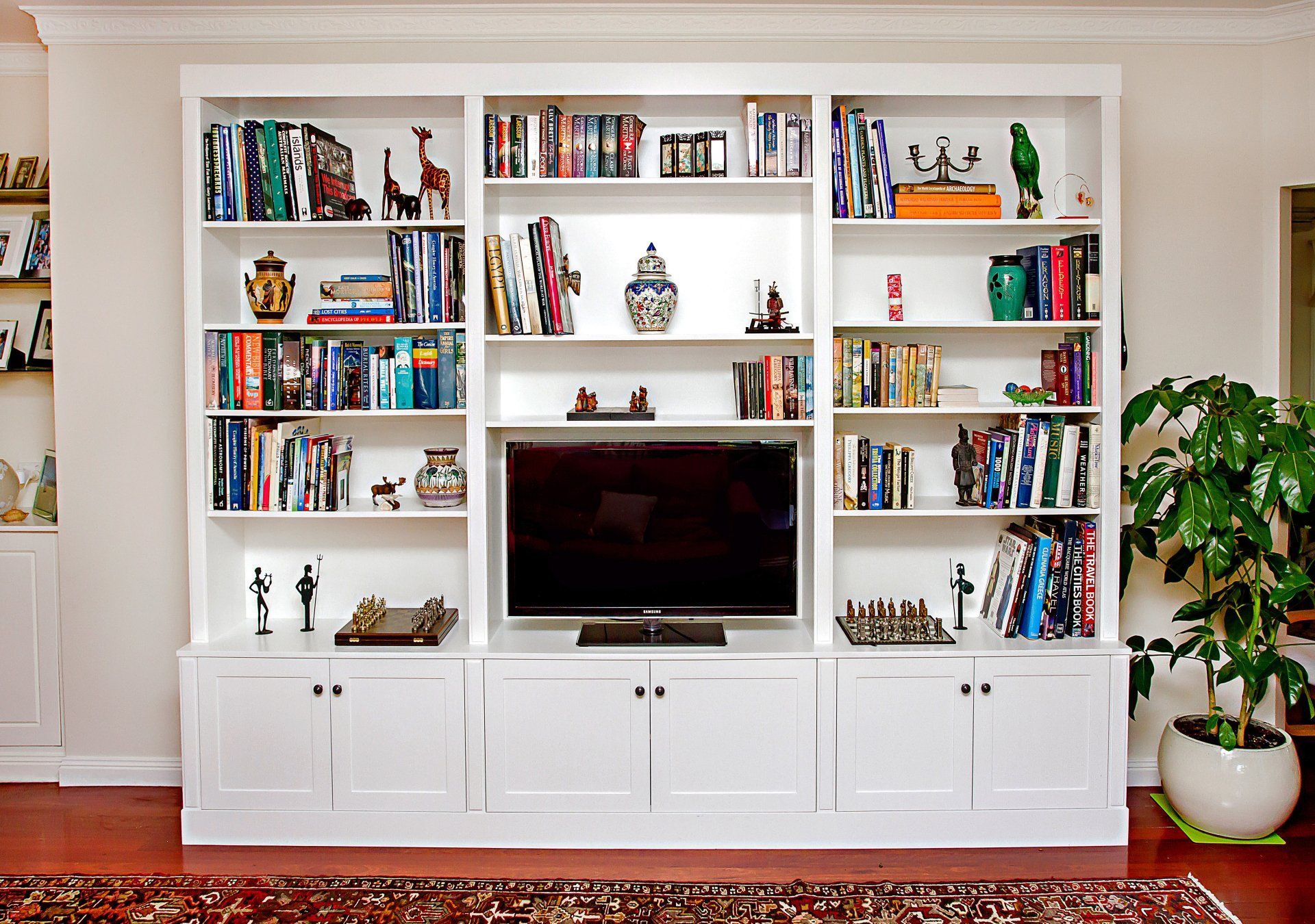 A Living Room Filled With Bookshelves And A Flat Screen Tv — Marlix Custom Timber Furniture Design and Joinery in Unanderra, NSW