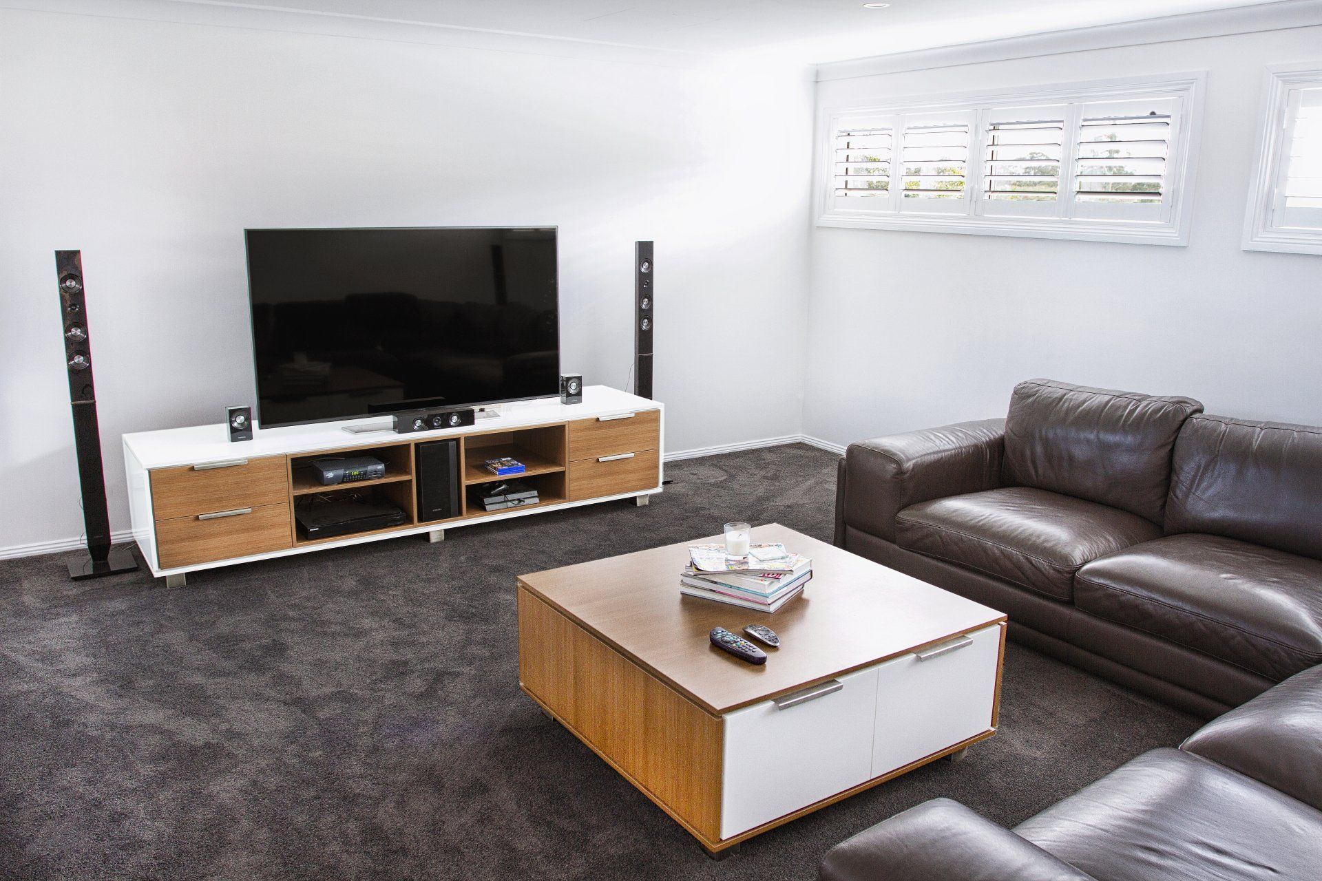 A Living Room With A Couch, Coffee Table, Television And Speakers — Marlix Custom Timber Furniture Design and Joinery in Unanderra, NSW