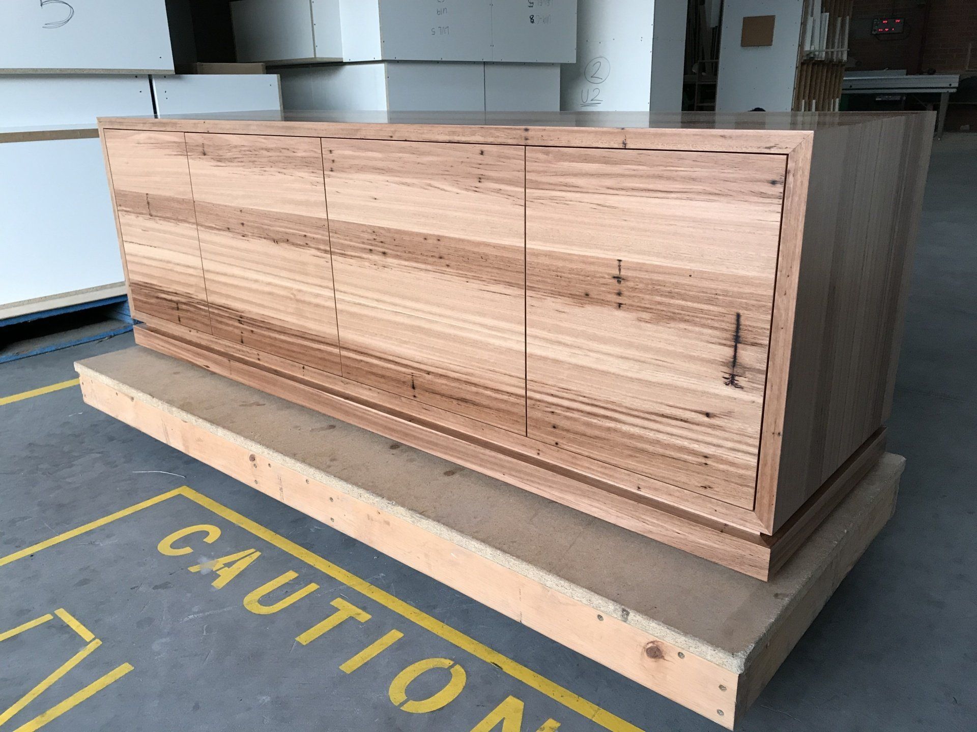A Wooden Cabinet Is Sitting On Top Of A Caution Sign — Marlix Custom Timber Furniture Design and Joinery in Unanderra, NSW