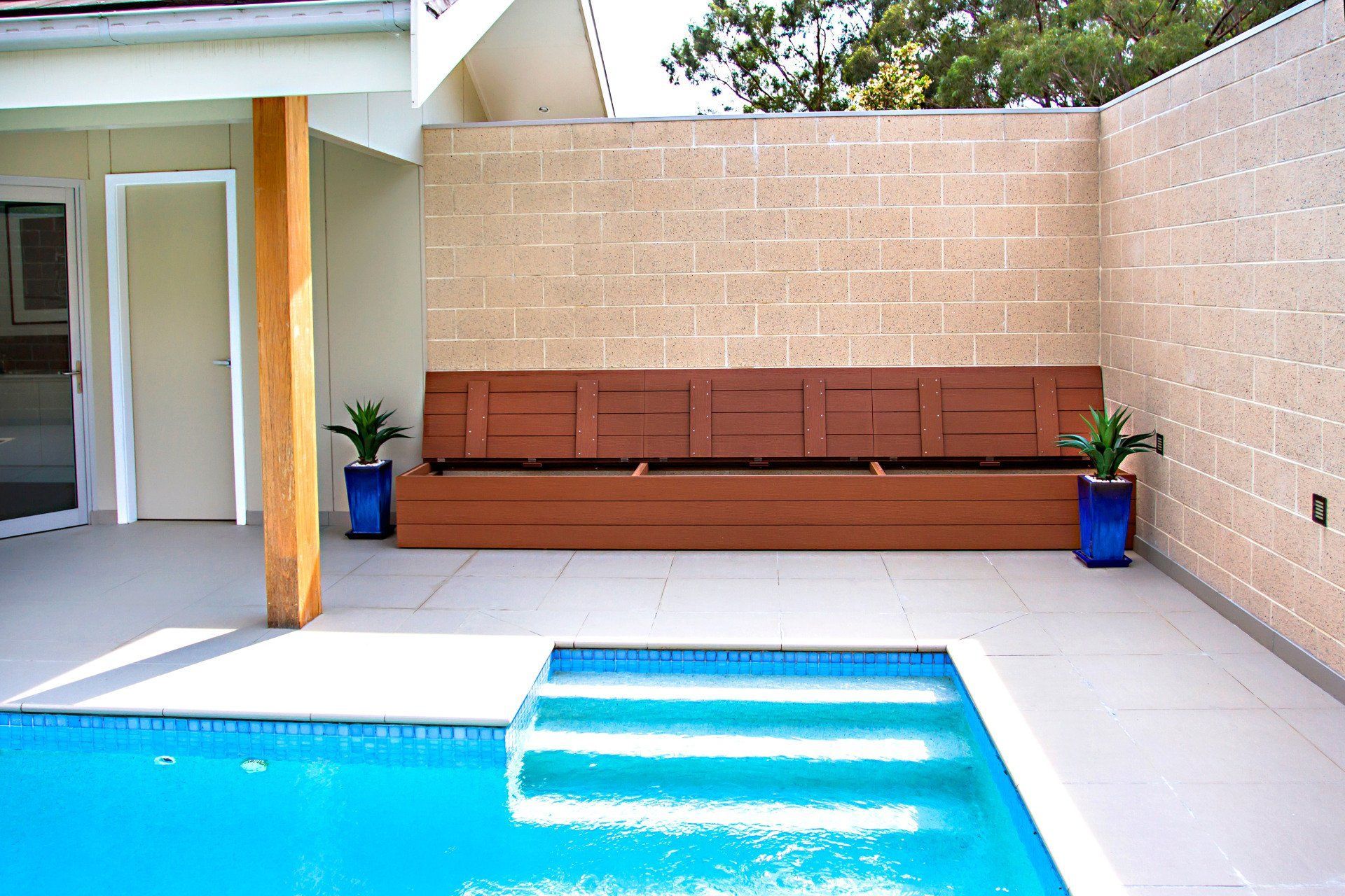 A Swimming Pool Surrounded By A Brick Wall And A Wooden Bench — Marlix Custom Timber Furniture Design and Joinery in Unanderra, NSW