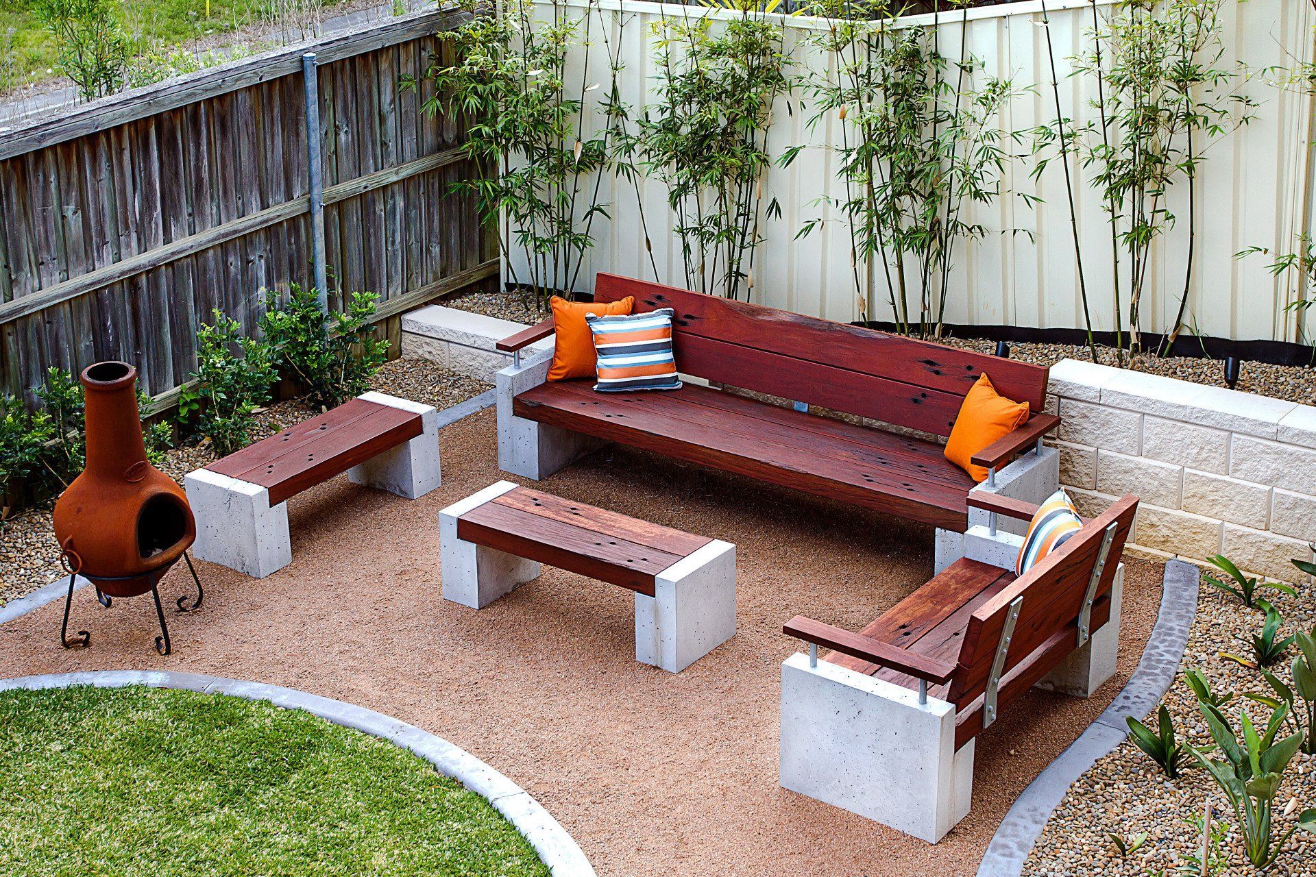 A Patio Area With A Couch And Benches And A Fireplace — Marlix Custom Timber Furniture Design and Joinery in Unanderra, NSW