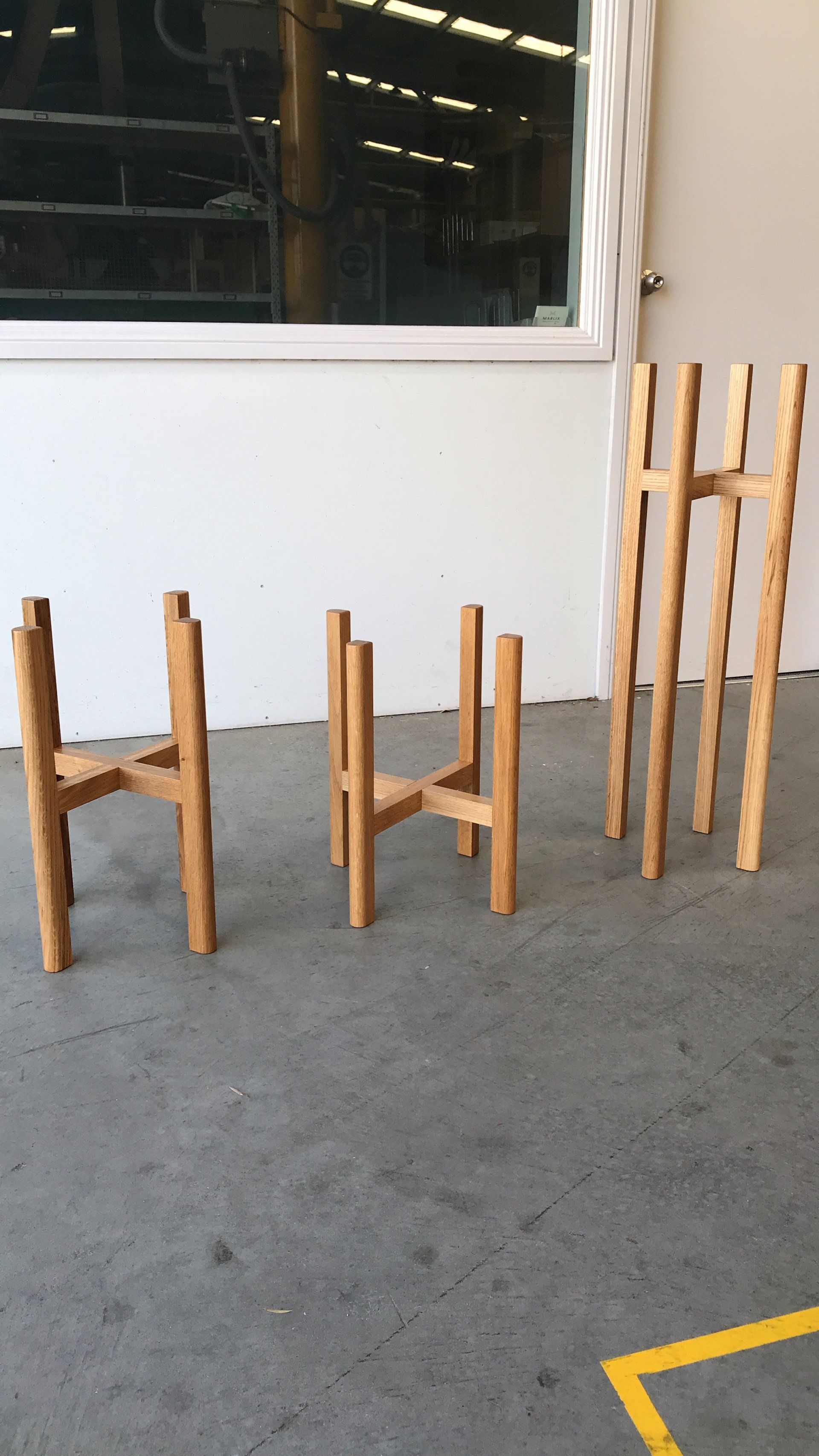 Three Wooden Chairs Are Sitting On A Concrete Floor In Front Of A Window — Marlix Custom Timber Furniture Design and Joinery in Unanderra, NSW