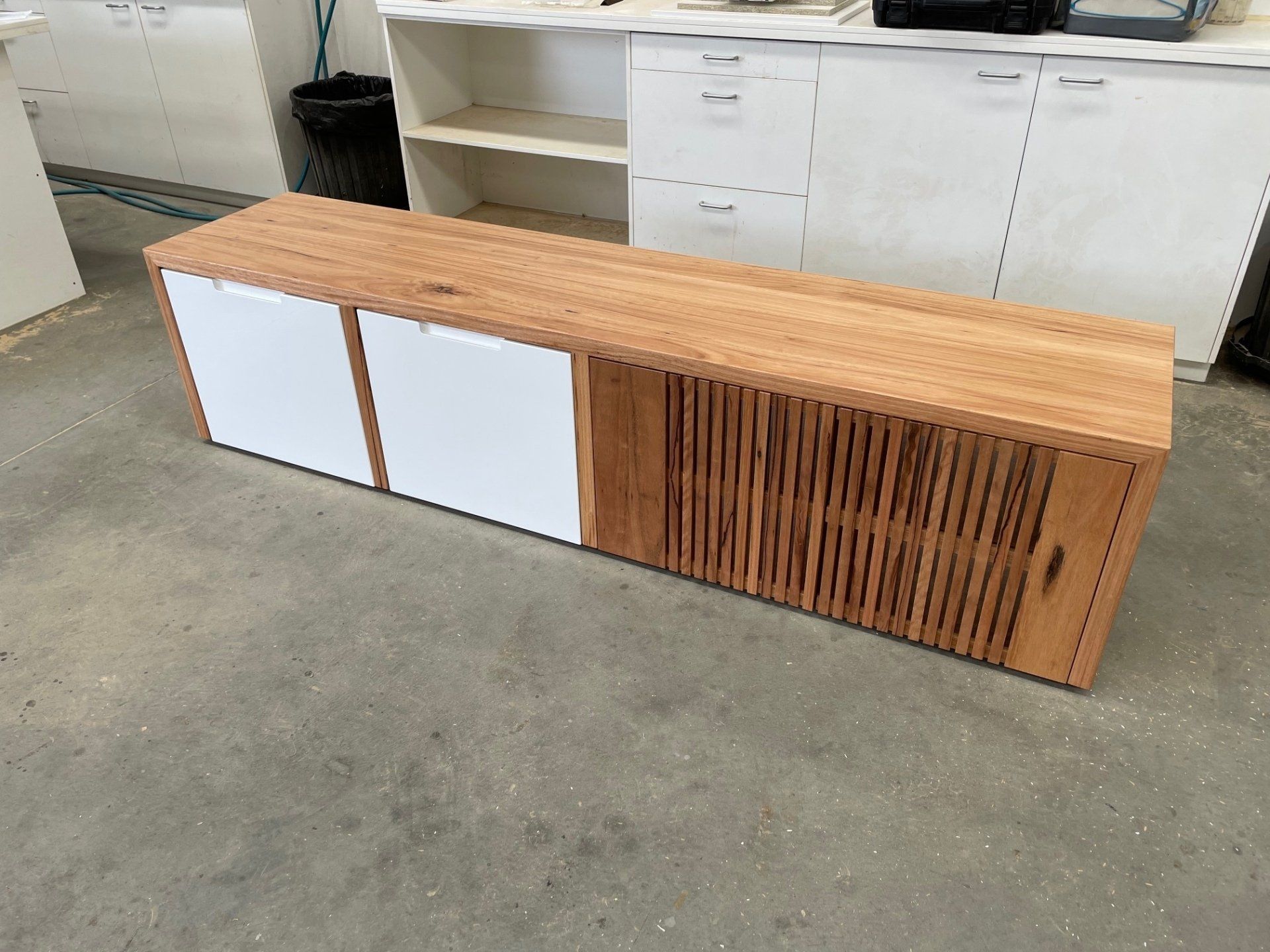 A Wooden Bench With White Doors Is Sitting On A Concrete Floor — Marlix Custom Timber Furniture Design and Joinery in Unanderra, NSW