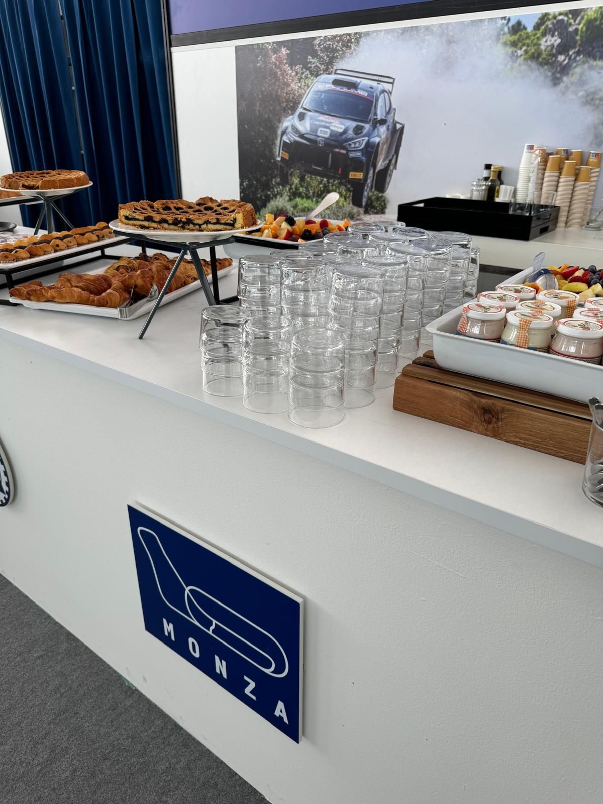Tavolo buffet con cibo, bevande e il logo dell'autodromo di Monza.
