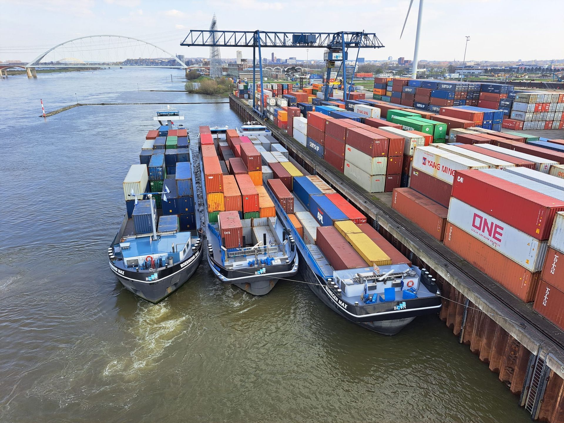 In een haven liggen drie boten gevuld met containers.
