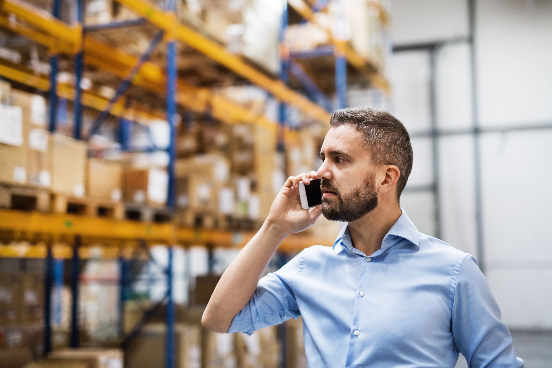 A man is talking on a cell phone in a warehouse.