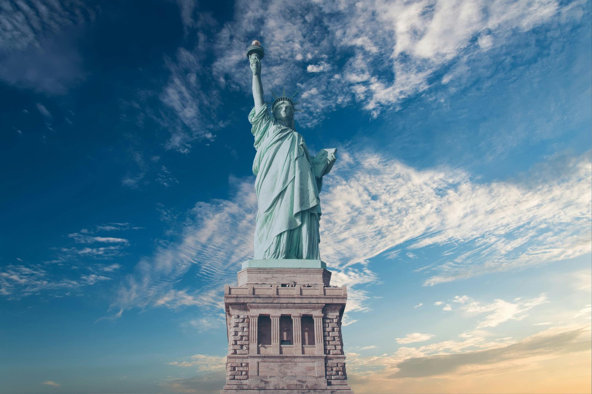 The statue of liberty is against a cloudy sky in new york city.