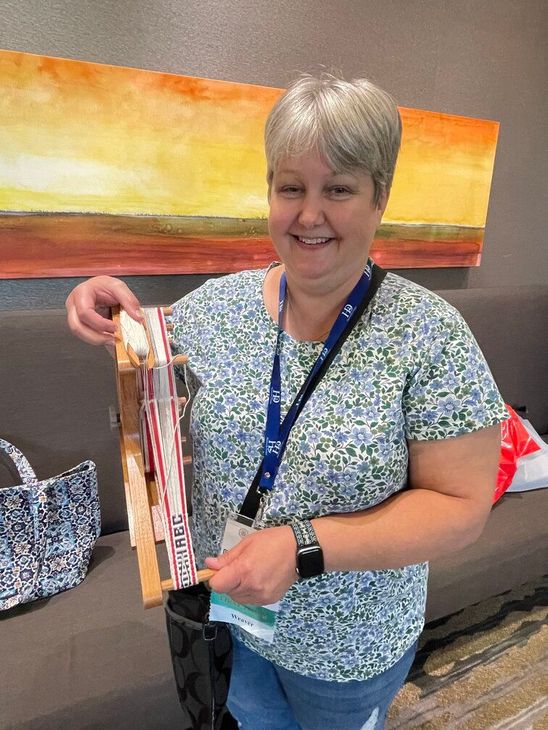 A weaver's guild member holding a loom in Fort Worth