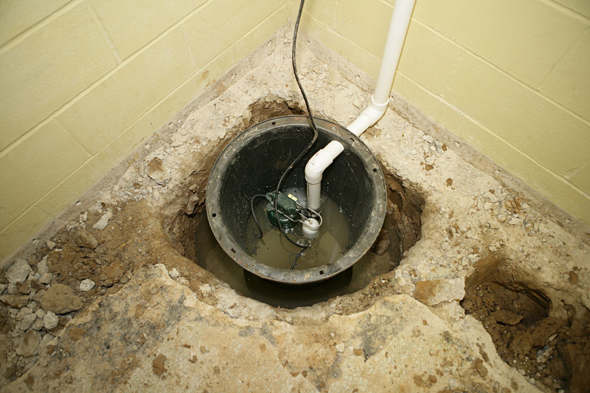 A sump pump is sitting in a hole in the ground.