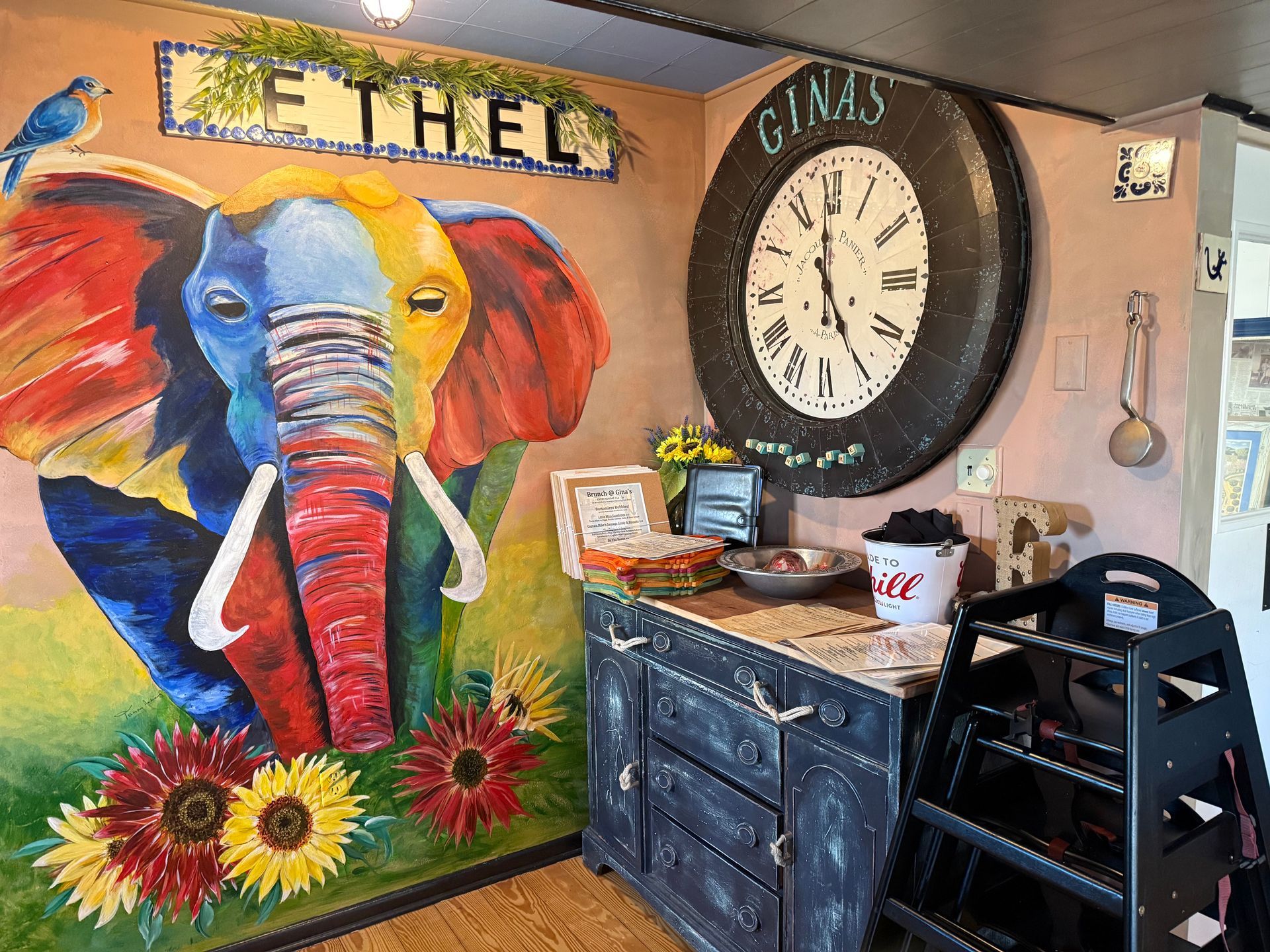 Painted elephant mural with sunflowers and huge clock on a wall