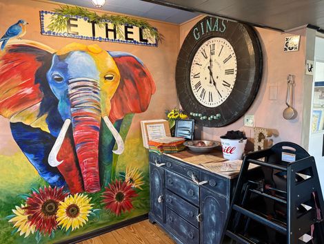 Painted elephant mural with sunflowers and huge clock on a wall