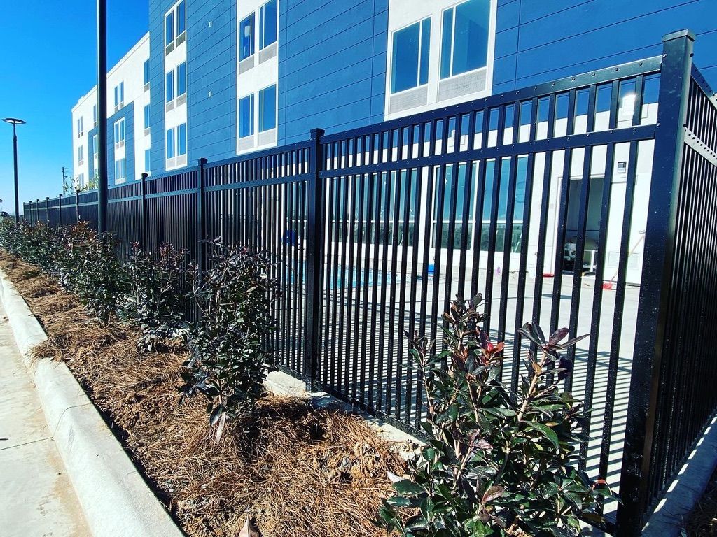 A black fence surrounds a building with a lot of windows