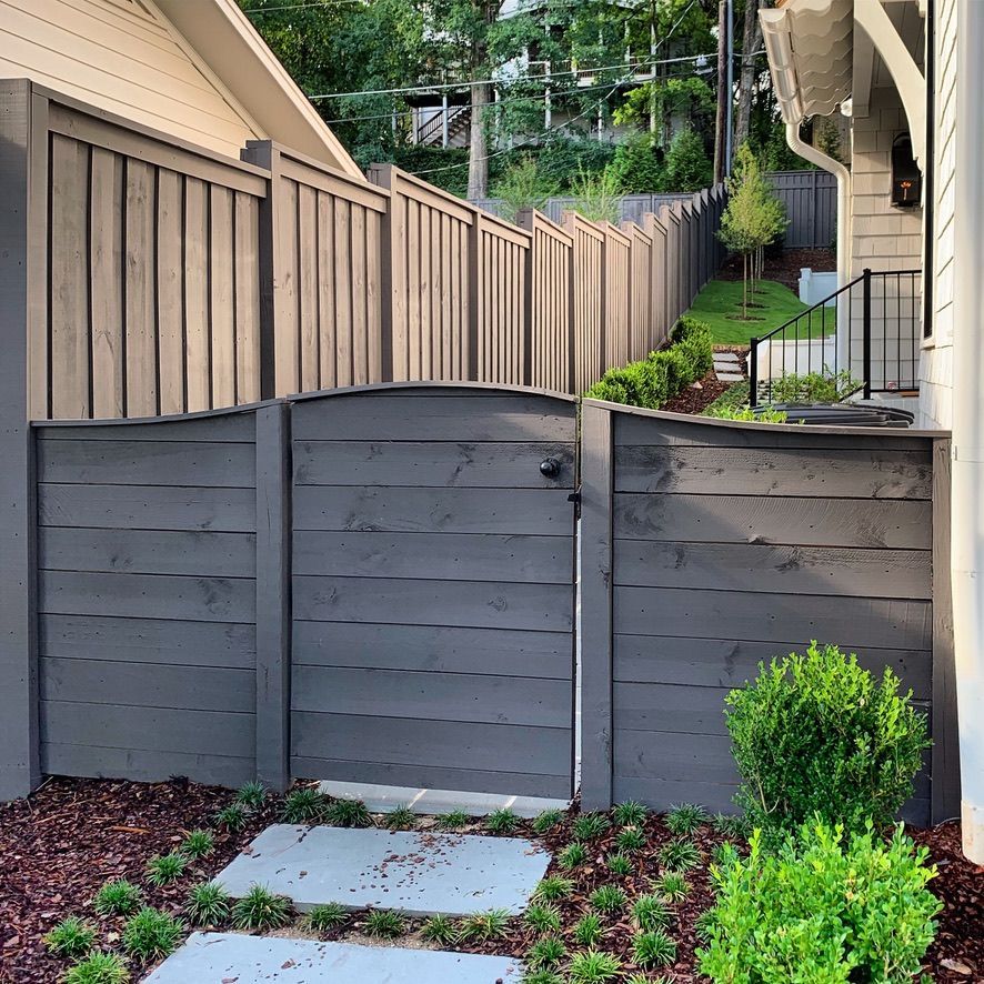 A wooden fence with a gate in front of a house