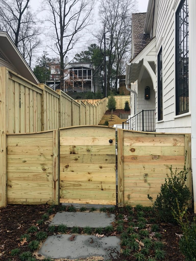 A wooden fence with a gate in front of a house.