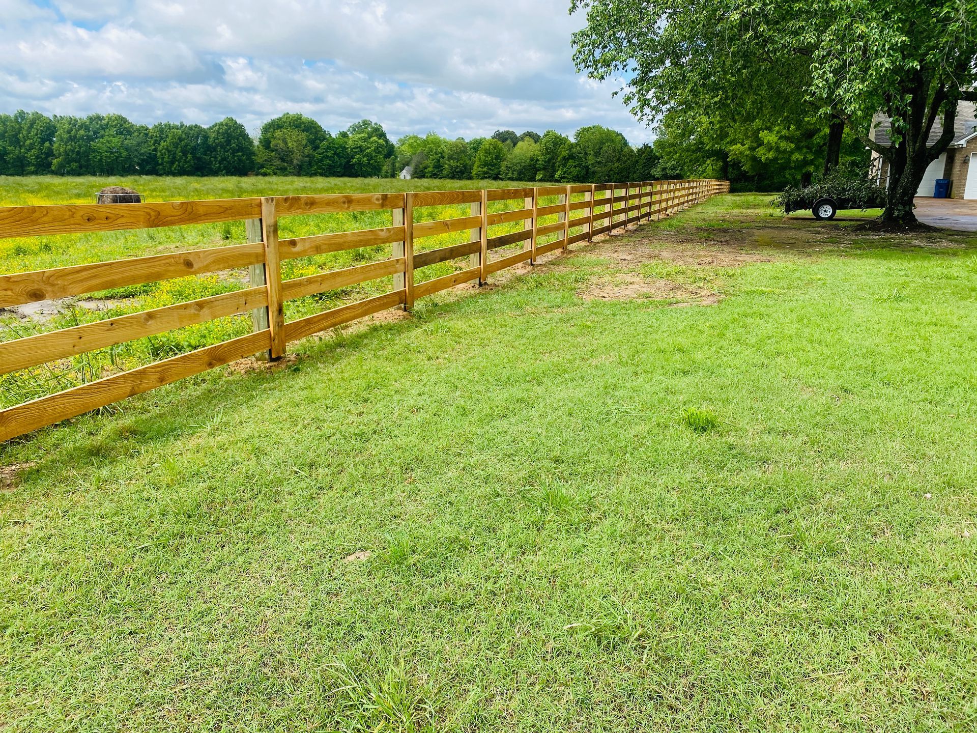 A wooden fence surrounds a lush green field.