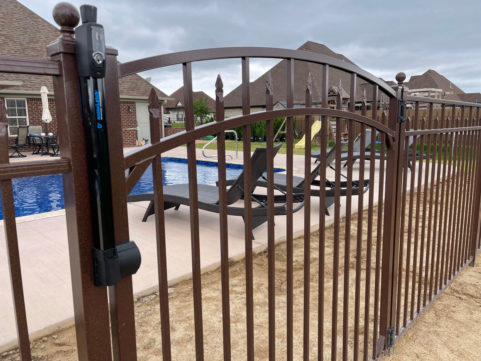 A brown metal fence surrounds a swimming pool.