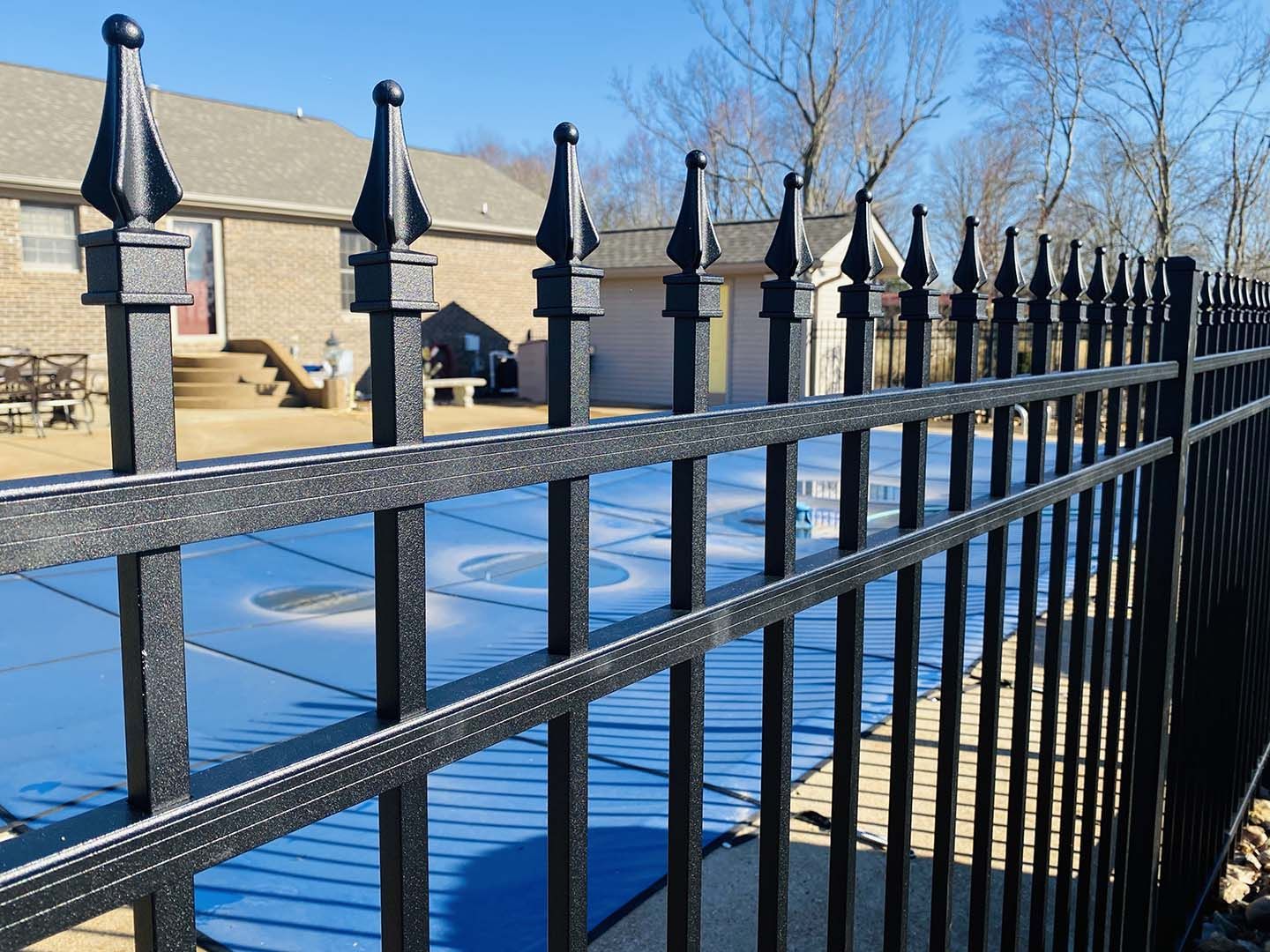 A black wrought iron fence surrounds a swimming pool.