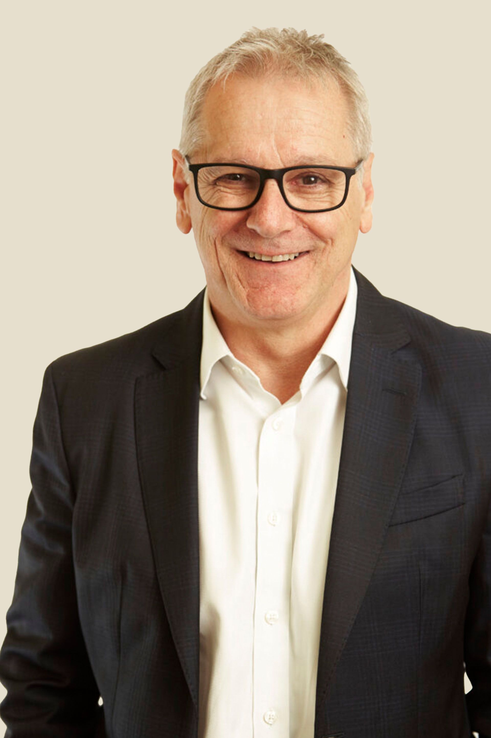 A man in a suit and glasses is smiling for the camera.