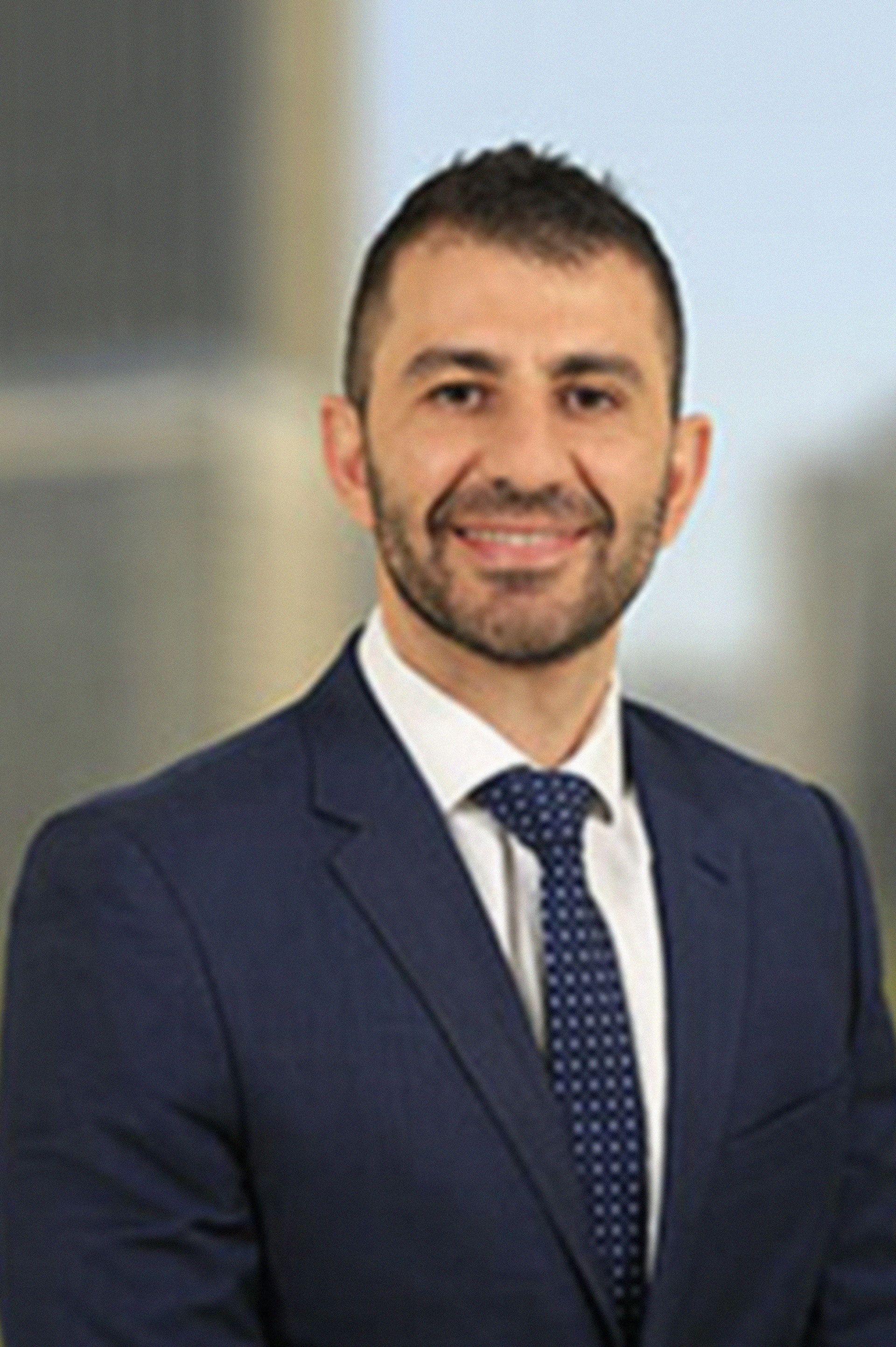 A man in a suit and tie is smiling for the camera.