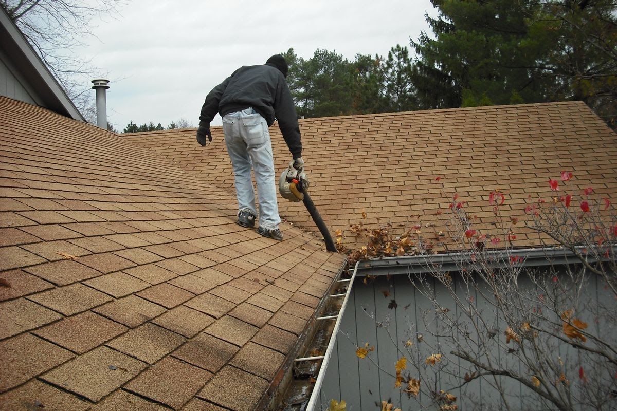 Professional contractor cleaning roof and gutters.