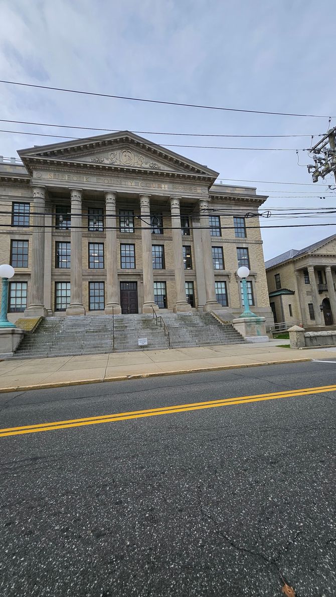 A judge holding a gavel at a desk with law documents and scales of justice in the background.