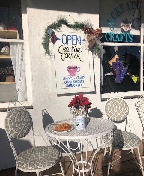 A table and chairs in front of a sign that says open creative corner