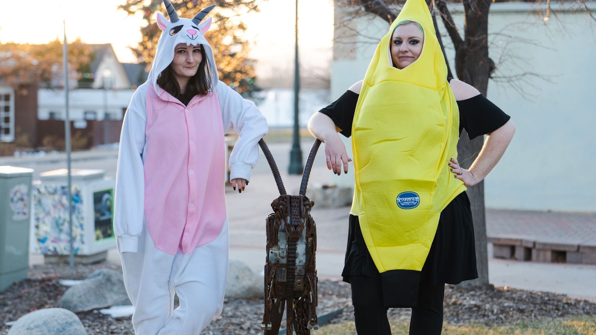 Two women in costumes are standing next to each other . one of the women is wearing a banana costume.